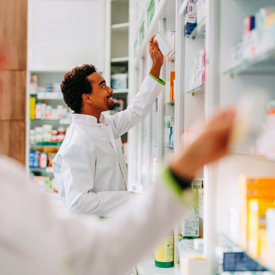 Pharmacist selecting medication from pharmacy shelf